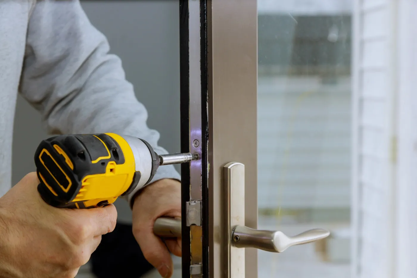 Artisan de l'équipe ajustant une serrure encastrée sur une porte d'entrée en Seine-Saint-Denis